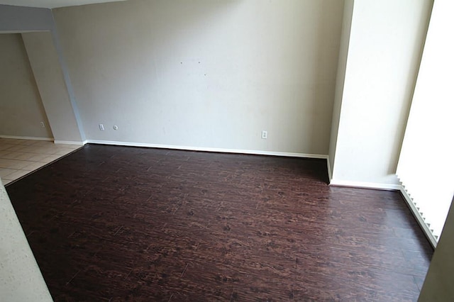 spare room featuring baseboards and wood finished floors