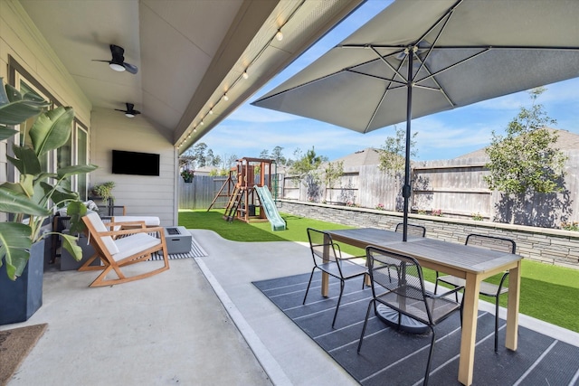 view of patio / terrace featuring outdoor dining space, a ceiling fan, a playground, and a fenced backyard