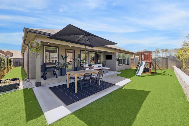 rear view of property featuring roof with shingles, a yard, a fenced backyard, a playground, and a patio area