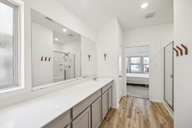 ensuite bathroom with visible vents, wood finished floors, connected bathroom, and a shower stall