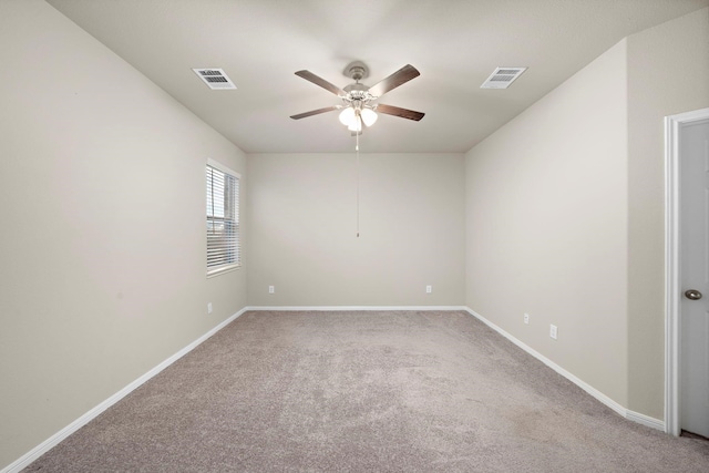 carpeted spare room with visible vents, baseboards, and ceiling fan