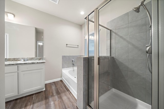 bathroom with a stall shower, a garden tub, wood finished floors, and vanity