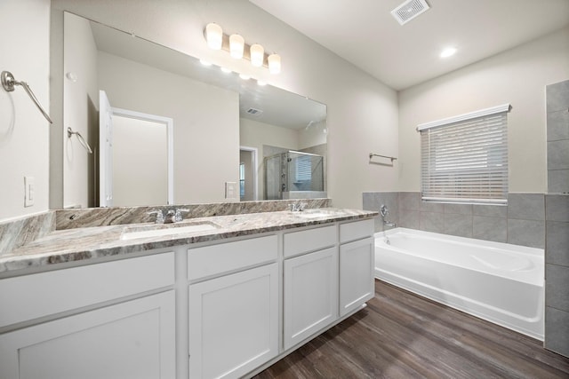 full bath with visible vents, a garden tub, a sink, wood finished floors, and a shower stall