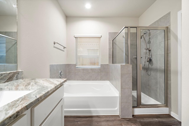 full bath featuring a shower stall, vanity, a garden tub, and wood finished floors