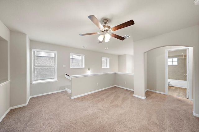 empty room with a wealth of natural light, visible vents, and light carpet