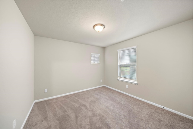 spare room featuring baseboards, carpet floors, and a textured ceiling