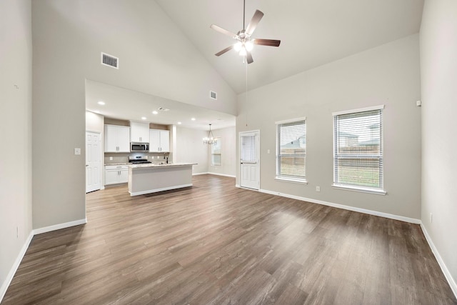 unfurnished living room with visible vents, high vaulted ceiling, wood finished floors, and ceiling fan with notable chandelier