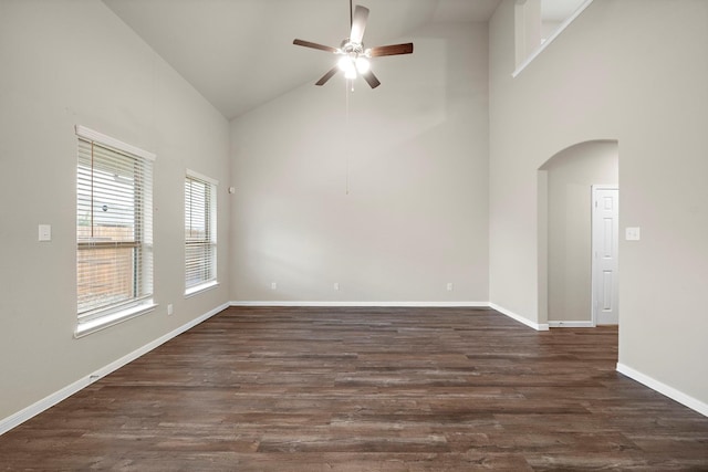 empty room with baseboards, ceiling fan, dark wood finished floors, arched walkways, and high vaulted ceiling