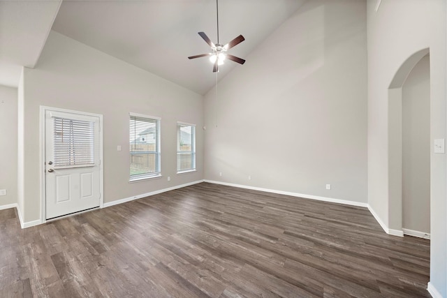 unfurnished room with baseboards, dark wood finished floors, arched walkways, high vaulted ceiling, and a ceiling fan