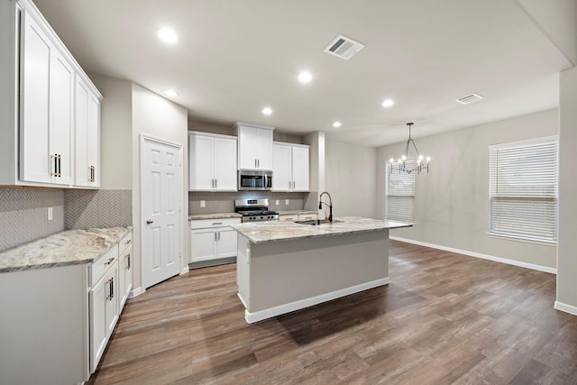 kitchen featuring visible vents, a sink, wood finished floors, white cabinetry, and appliances with stainless steel finishes