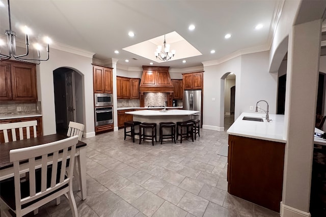 kitchen with a breakfast bar, appliances with stainless steel finishes, arched walkways, a notable chandelier, and a sink