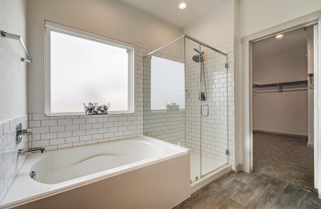 bathroom featuring a garden tub, a stall shower, wood finished floors, recessed lighting, and a spacious closet