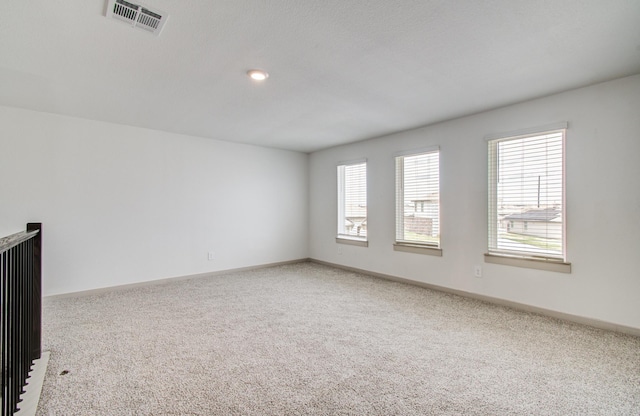 spare room featuring visible vents, baseboards, and carpet flooring