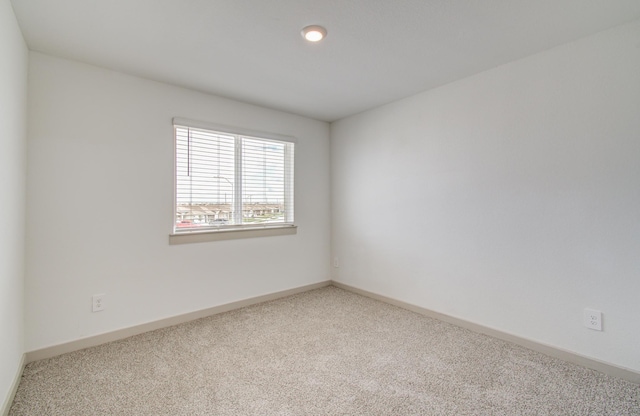 carpeted empty room featuring baseboards