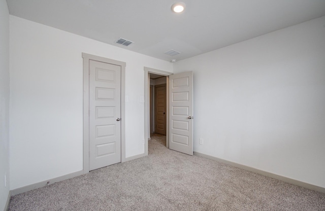 unfurnished room featuring carpet, visible vents, and baseboards