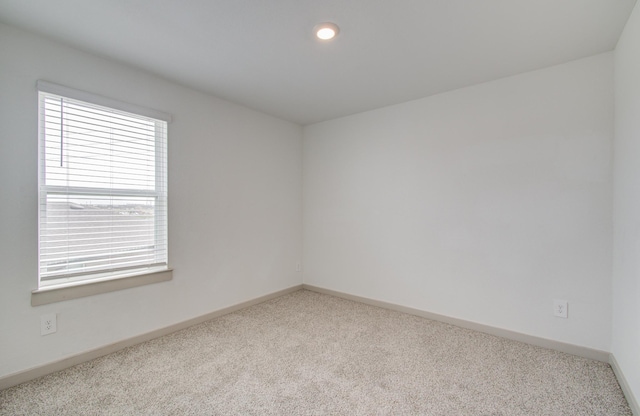 unfurnished room with carpet and baseboards