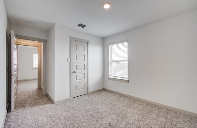 unfurnished bedroom featuring visible vents, light carpet, and baseboards