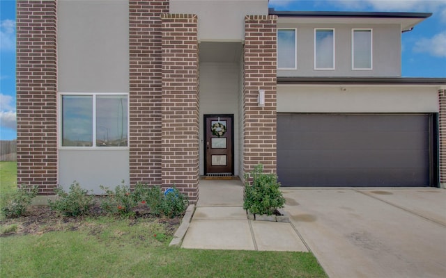 view of front of house with brick siding, stucco siding, an attached garage, and concrete driveway