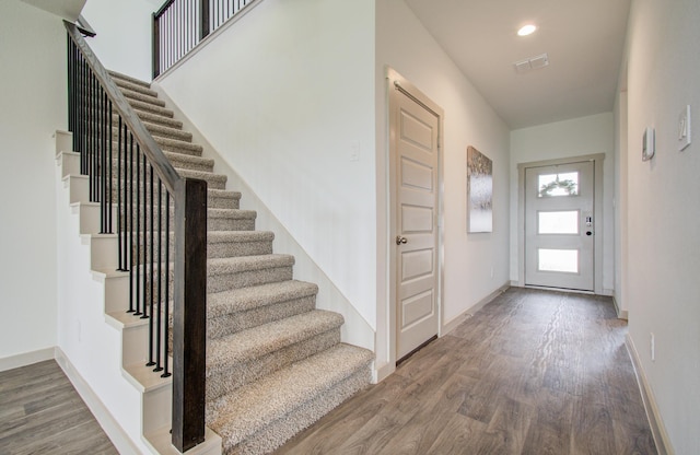 entrance foyer with stairway, visible vents, and wood finished floors