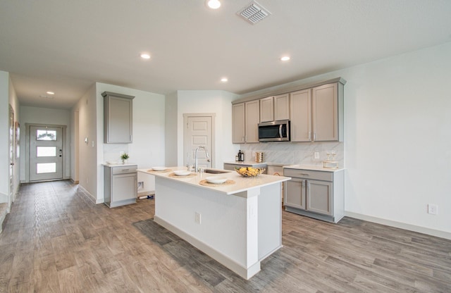 kitchen with stainless steel microwave, gray cabinets, visible vents, and a sink