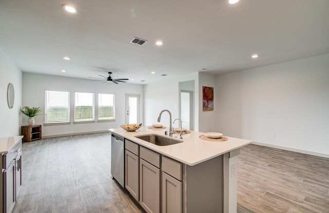 kitchen featuring gray cabinetry, a sink, stainless steel dishwasher, open floor plan, and light countertops