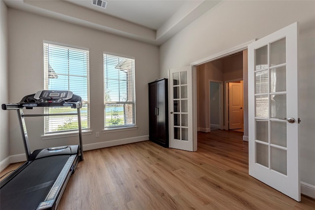 exercise room featuring french doors, light wood-type flooring, and baseboards