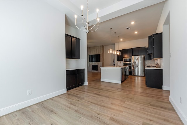 kitchen featuring a sink, stainless steel appliances, light wood-style floors, light countertops, and a chandelier