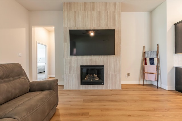 living room featuring a fireplace, light wood-type flooring, and baseboards