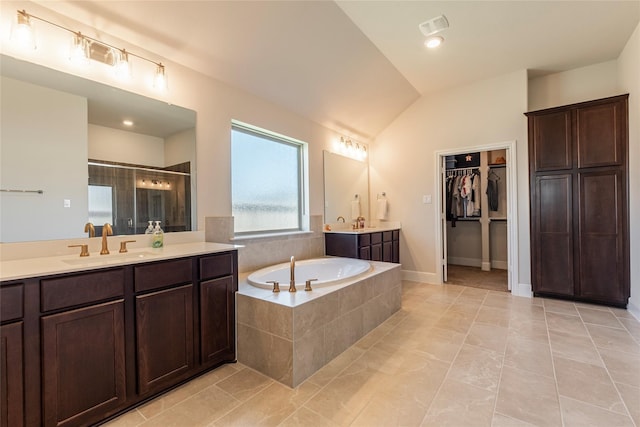 full bathroom with lofted ceiling, two vanities, a stall shower, a sink, and a garden tub