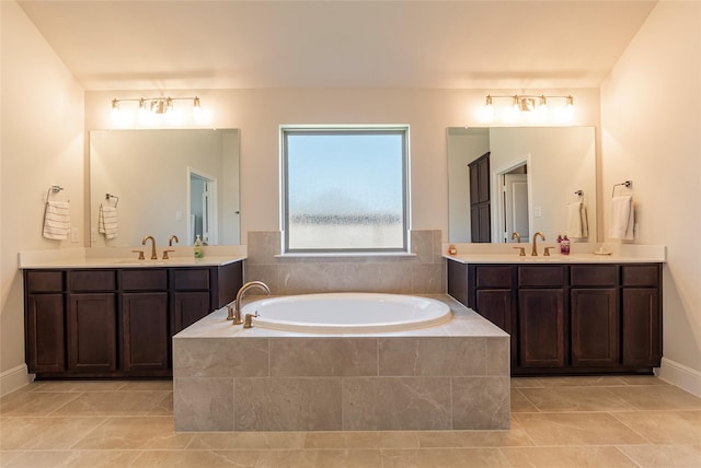 full bath featuring a bath, a sink, and two vanities