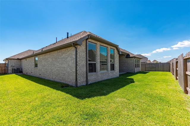 view of side of property featuring a lawn, central AC unit, a fenced backyard, and brick siding