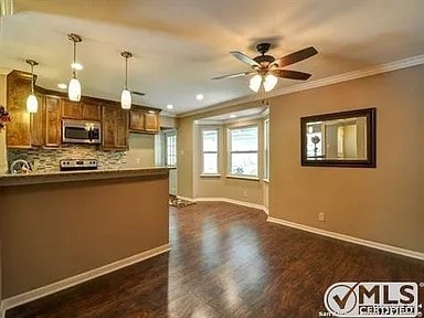 kitchen with a ceiling fan, a peninsula, ornamental molding, decorative backsplash, and stainless steel microwave