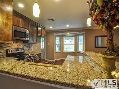 kitchen with ornamental molding, appliances with stainless steel finishes, and light stone countertops