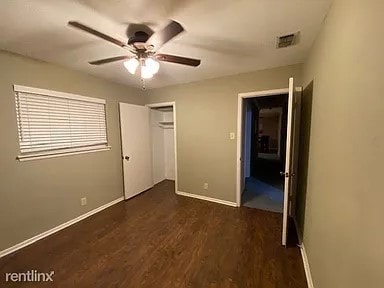 unfurnished bedroom featuring visible vents, ceiling fan, baseboards, a closet, and dark wood-style flooring