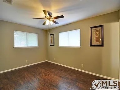 empty room with visible vents, baseboards, dark wood-type flooring, and ceiling fan