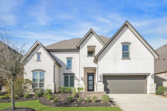 french country inspired facade with a shingled roof, stucco siding, concrete driveway, a garage, and stone siding