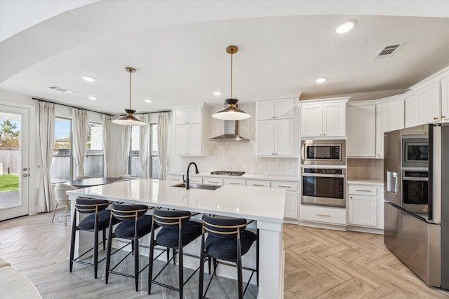 kitchen featuring visible vents, a sink, stainless steel appliances, light countertops, and backsplash