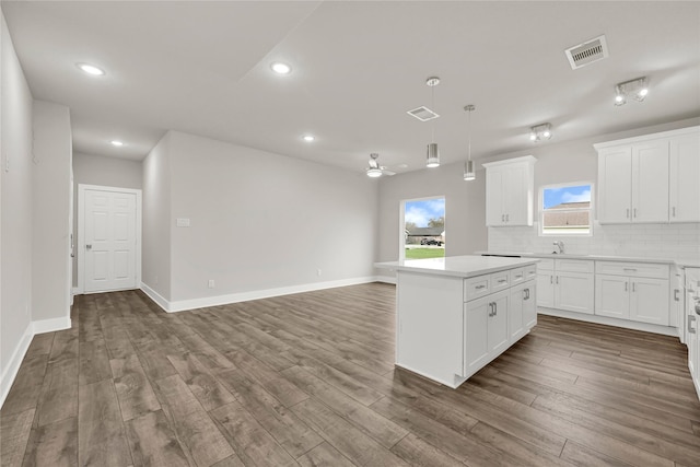 kitchen with backsplash, visible vents, a kitchen island, and dark wood-style flooring