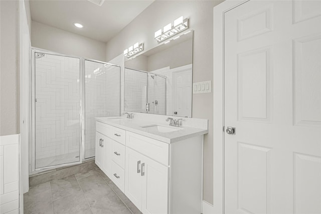 bathroom featuring a sink, a stall shower, and double vanity