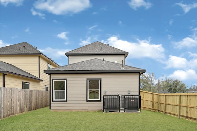 back of house featuring central air condition unit, a lawn, roof with shingles, and a fenced backyard