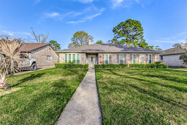 ranch-style home with brick siding, a chimney, and a front lawn