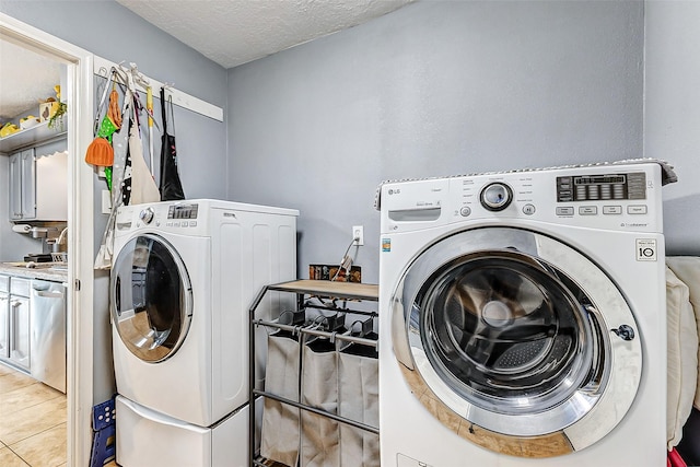 clothes washing area featuring washer and dryer, a textured ceiling, light tile patterned flooring, and laundry area