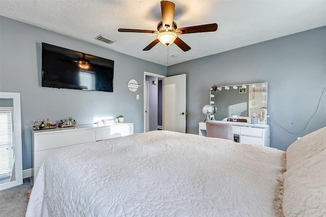 bedroom with a textured ceiling, visible vents, carpet floors, and ceiling fan