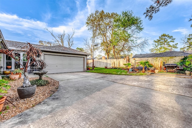 garage with concrete driveway and fence