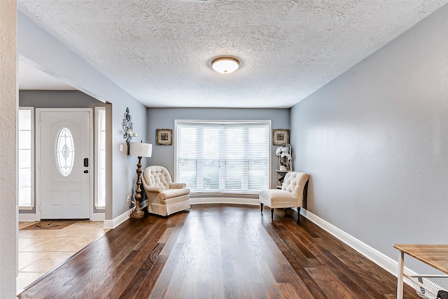 foyer entrance with wood finished floors, baseboards, and a textured ceiling