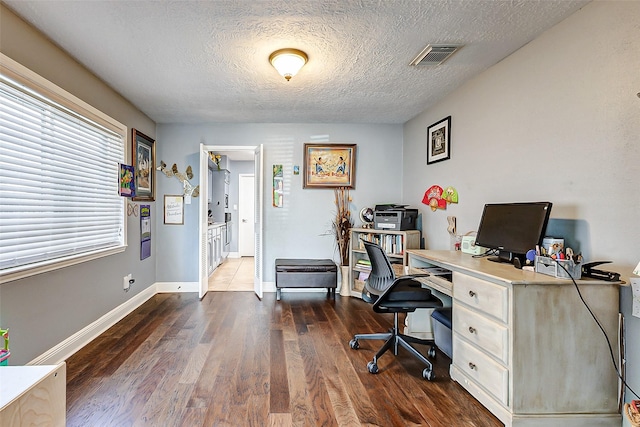 home office with dark wood finished floors, visible vents, a textured ceiling, and baseboards