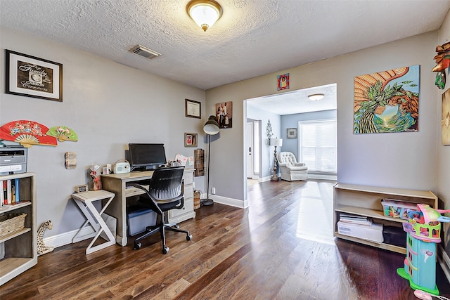 office area featuring a textured ceiling, wood finished floors, visible vents, and baseboards