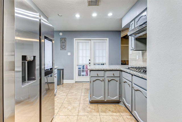 kitchen featuring visible vents, a peninsula, light tile patterned flooring, gray cabinets, and appliances with stainless steel finishes