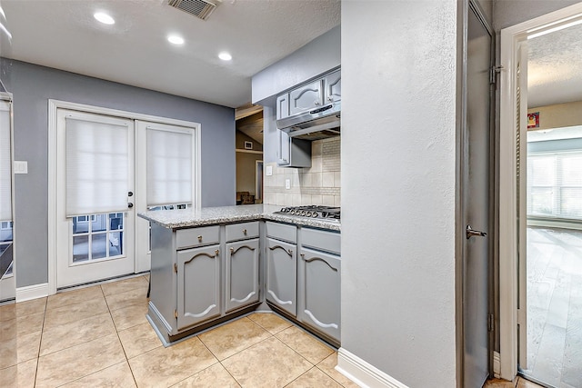 kitchen with light tile patterned floors, visible vents, a peninsula, and gray cabinets