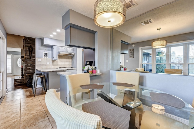 kitchen with decorative backsplash, a peninsula, light tile patterned flooring, and visible vents